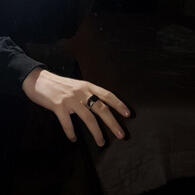 A pale hand on a black background, it's reaching out gently, palm down.